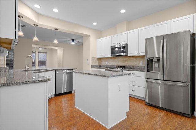 kitchen featuring ceiling fan, sink, hanging light fixtures, stainless steel appliances, and kitchen peninsula