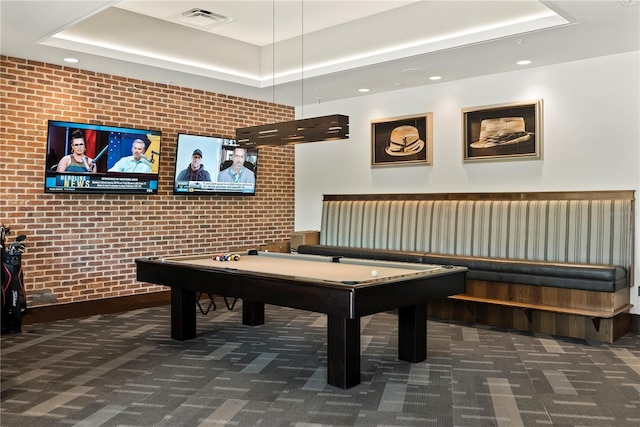 rec room with a tray ceiling, dark carpet, brick wall, and billiards