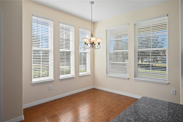 dining space with a healthy amount of sunlight, dark hardwood / wood-style floors, and an inviting chandelier