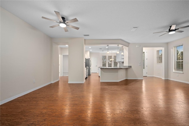 unfurnished living room featuring ceiling fan, hardwood / wood-style floors, a textured ceiling, and sink