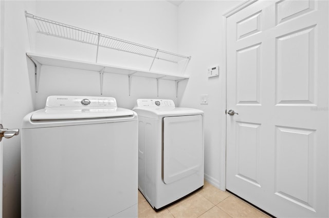 clothes washing area featuring washer and clothes dryer and light tile patterned floors