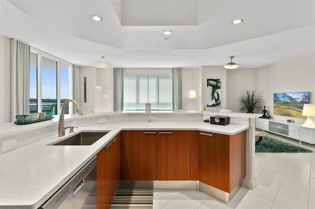 kitchen with sink, a center island, stainless steel dishwasher, a tray ceiling, and light tile patterned floors