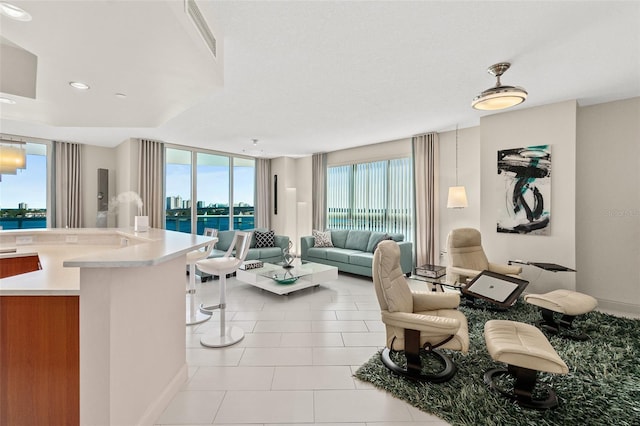 tiled living room featuring a water view and a healthy amount of sunlight