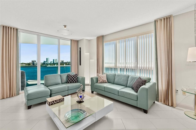 living room featuring a textured ceiling, a water view, and light tile patterned flooring