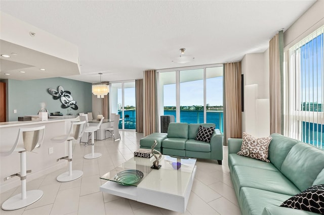 tiled living room with a water view, a wealth of natural light, and a notable chandelier