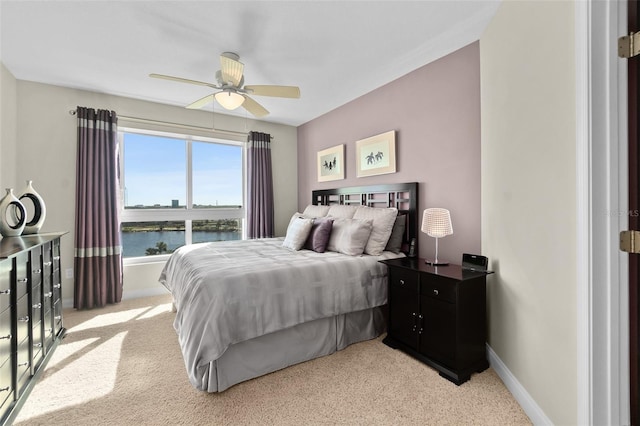 bedroom featuring light carpet, a water view, and ceiling fan