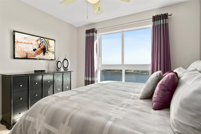 bedroom with ceiling fan and a water view