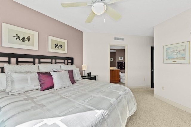 bedroom featuring ceiling fan, light colored carpet, and ensuite bath