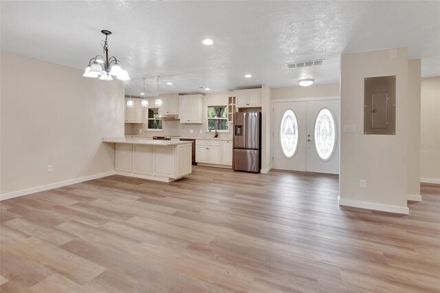 kitchen with kitchen peninsula, stainless steel fridge, french doors, light hardwood / wood-style flooring, and electric panel