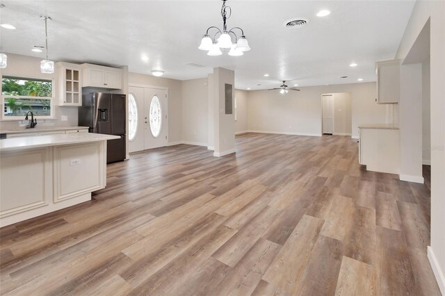 kitchen with ceiling fan with notable chandelier, sink, light wood-type flooring, decorative light fixtures, and stainless steel fridge with ice dispenser