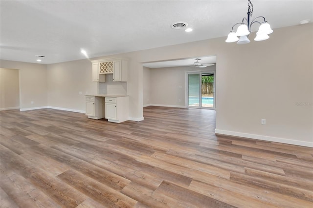 unfurnished living room with ceiling fan with notable chandelier and light hardwood / wood-style floors