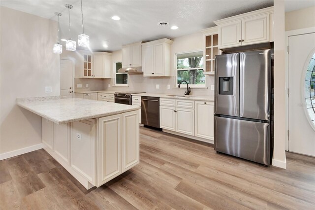 kitchen featuring pendant lighting, sink, light wood-type flooring, appliances with stainless steel finishes, and kitchen peninsula