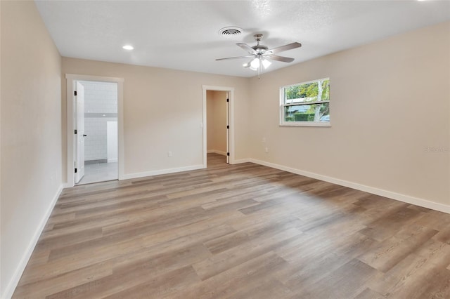 empty room with ceiling fan and light hardwood / wood-style flooring