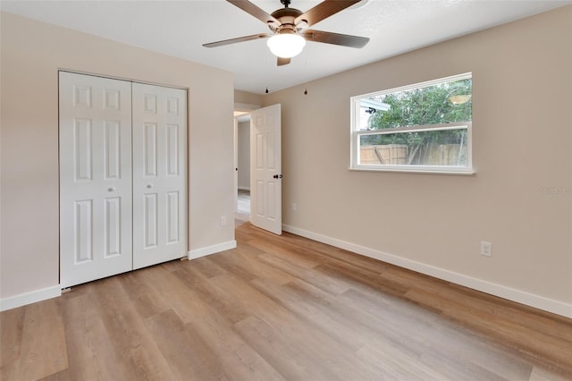 unfurnished bedroom featuring ceiling fan, light wood-type flooring, and a closet