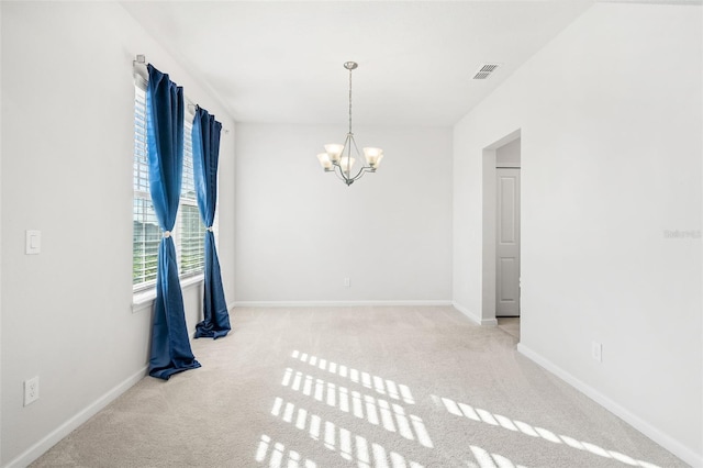 carpeted spare room featuring a chandelier