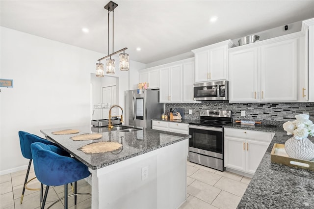 kitchen featuring sink, backsplash, a kitchen island with sink, light tile patterned floors, and appliances with stainless steel finishes