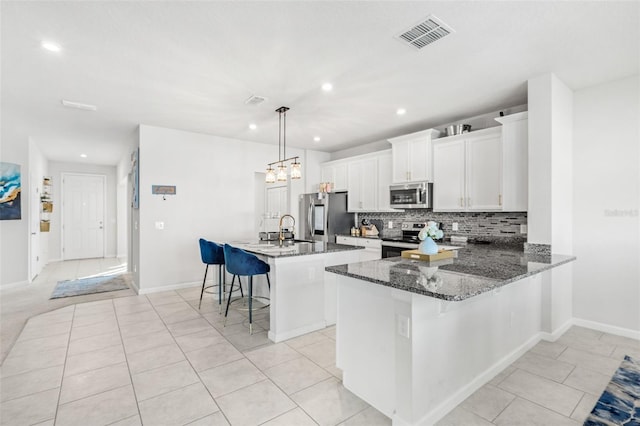 kitchen with pendant lighting, a center island, dark stone counters, a kitchen breakfast bar, and stainless steel appliances