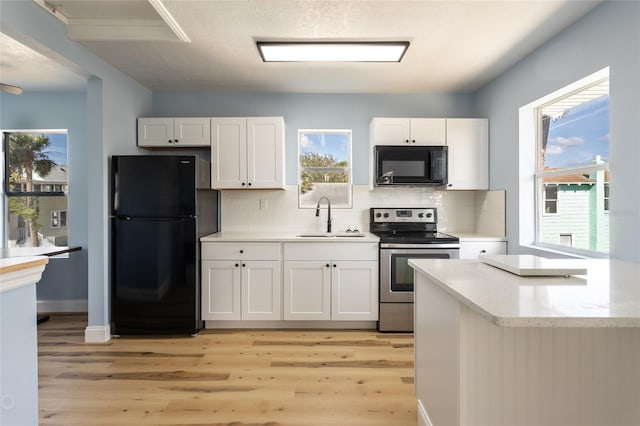 kitchen with sink, light hardwood / wood-style flooring, white cabinetry, and black appliances