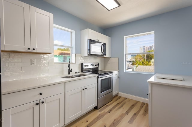 kitchen featuring white cabinets, stainless steel appliances, a healthy amount of sunlight, and sink