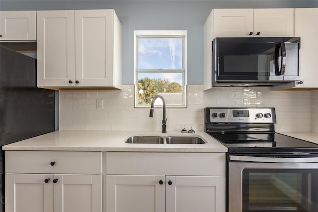 kitchen with electric range, sink, light stone countertops, decorative backsplash, and white cabinets