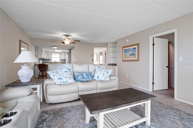 living room featuring light tile patterned floors, ceiling fan, and sink