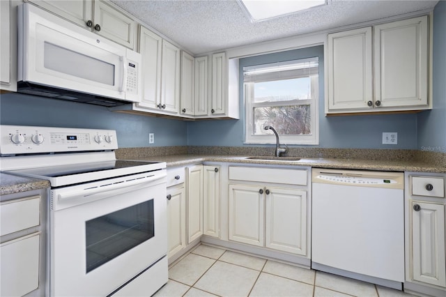 kitchen with light tile patterned floors, white appliances, a textured ceiling, and sink