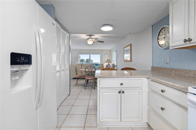 kitchen featuring white cabinets, kitchen peninsula, white fridge with ice dispenser, and ceiling fan