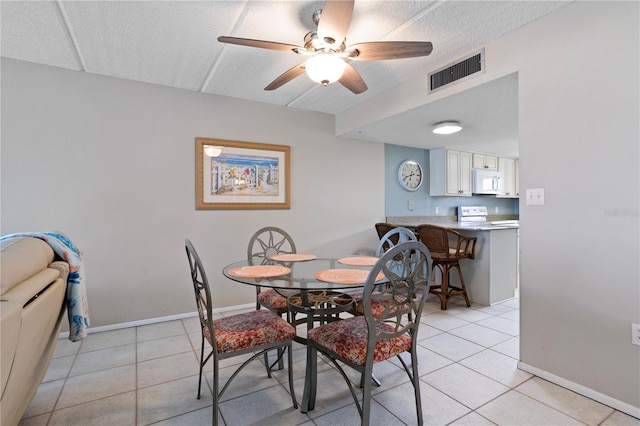 dining room with ceiling fan, light tile patterned floors, and a textured ceiling