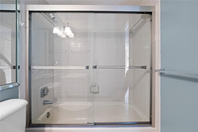 bathroom with toilet and shower / bath combination with glass door