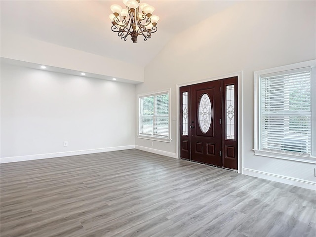 entryway featuring hardwood / wood-style floors, a notable chandelier, and high vaulted ceiling