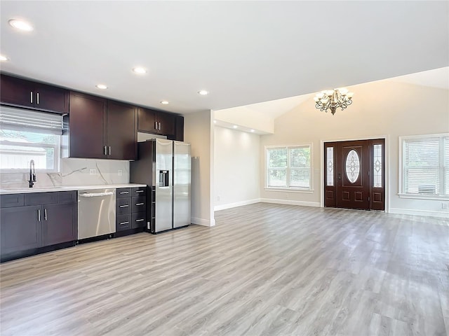 kitchen featuring light wood-type flooring, stainless steel appliances, sink, an inviting chandelier, and lofted ceiling