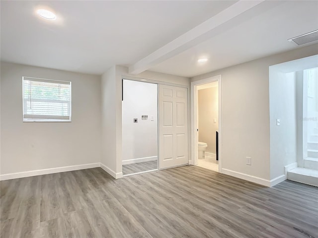 empty room with beam ceiling and hardwood / wood-style floors