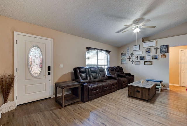 living room with a textured ceiling, light wood-type flooring, vaulted ceiling, and ceiling fan