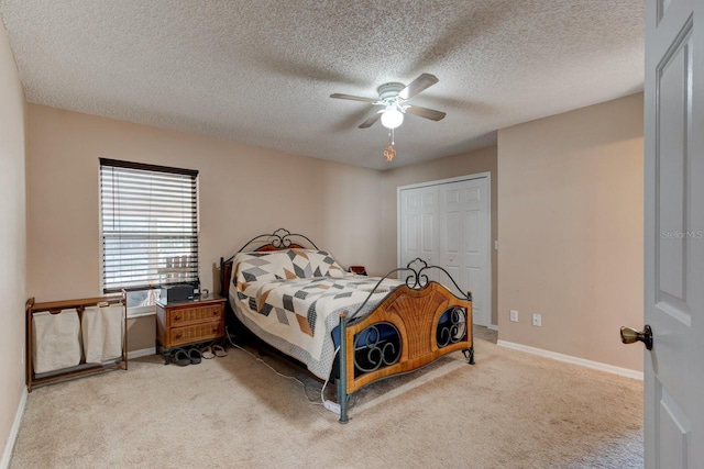 bedroom featuring ceiling fan, light colored carpet, a textured ceiling, and a closet