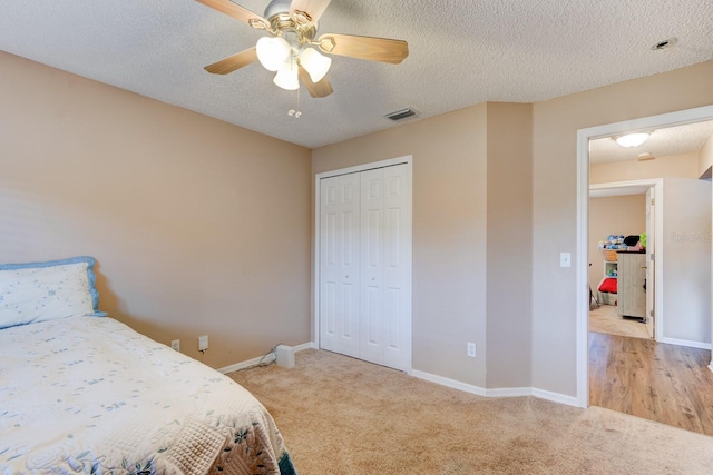 carpeted bedroom featuring a textured ceiling, a closet, and ceiling fan