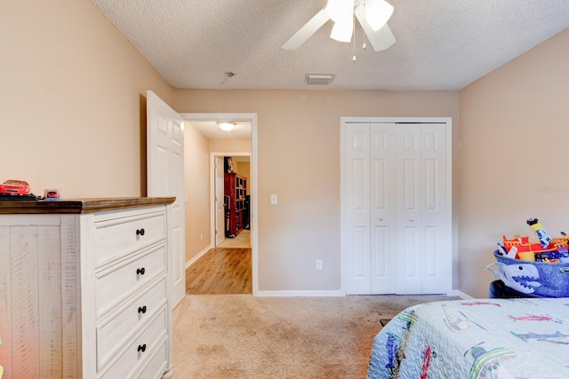 carpeted bedroom with ceiling fan, a textured ceiling, and a closet