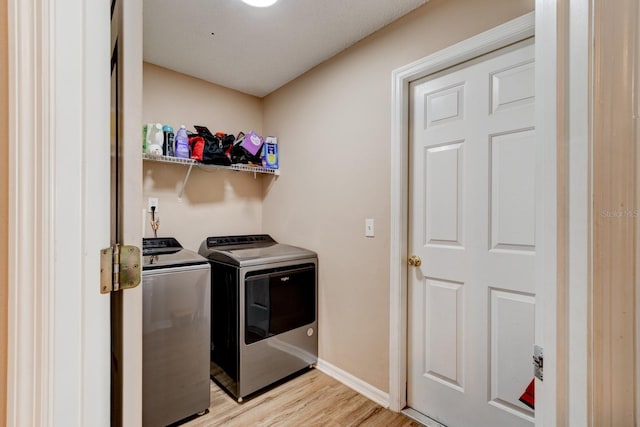 clothes washing area featuring independent washer and dryer and light hardwood / wood-style flooring