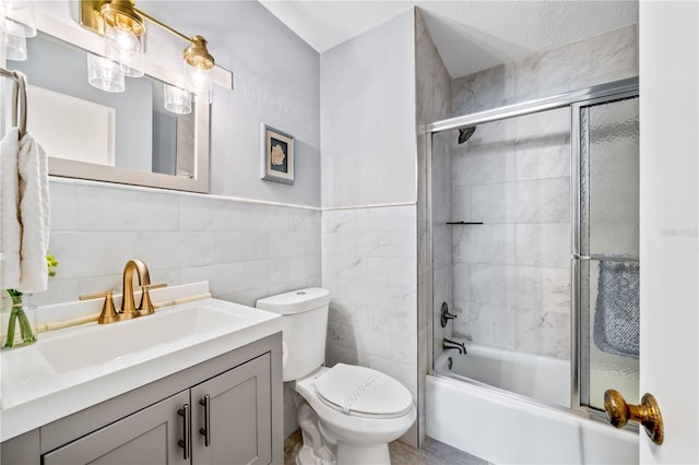 full bathroom featuring vanity, toilet, shower / bath combination with glass door, and tile walls