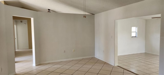 empty room featuring ceiling fan, light tile patterned flooring, and a textured ceiling