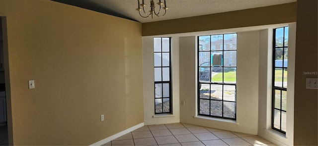 doorway with plenty of natural light, light tile patterned floors, a textured ceiling, and an inviting chandelier