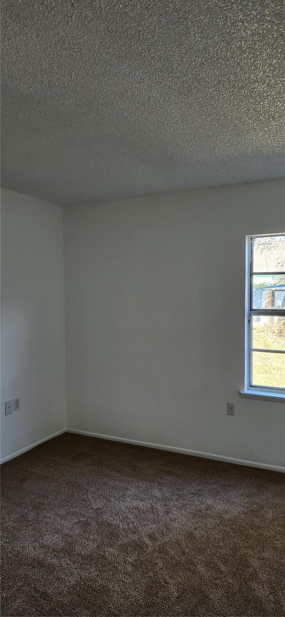 unfurnished room with dark colored carpet and a textured ceiling