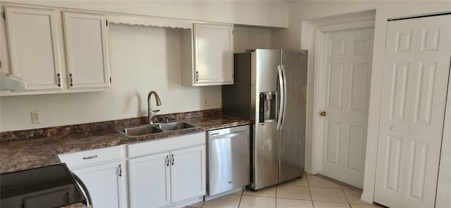 kitchen featuring dark stone counters, stainless steel appliances, sink, light tile patterned floors, and white cabinets