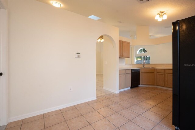 kitchen featuring sink, light tile patterned floors, black appliances, and a textured ceiling