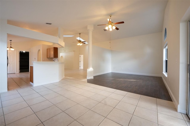 unfurnished room featuring ornate columns, ceiling fan, light hardwood / wood-style floors, and vaulted ceiling