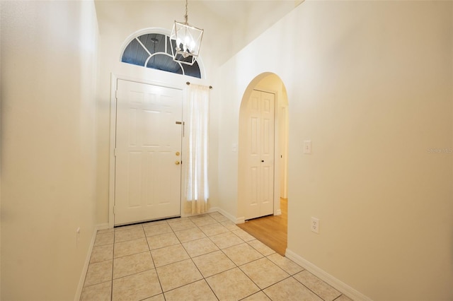 tiled foyer featuring a chandelier and a high ceiling