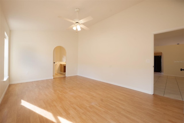 empty room featuring ceiling fan, high vaulted ceiling, and light hardwood / wood-style flooring