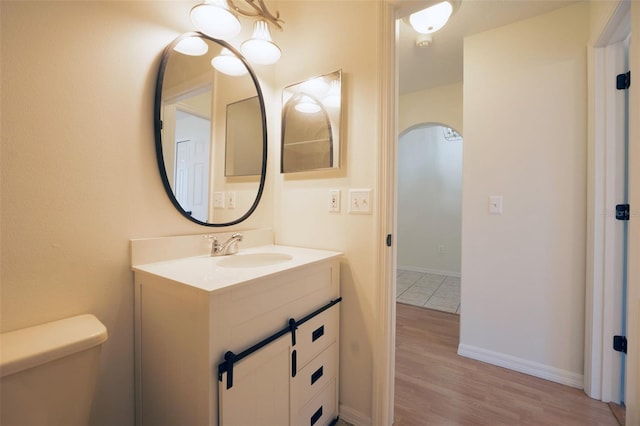 bathroom with wood-type flooring, vanity, and toilet