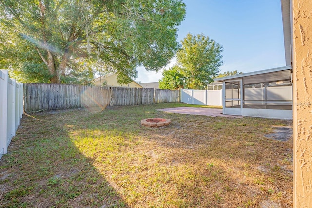 view of yard with a sunroom, a patio, and an outdoor fire pit