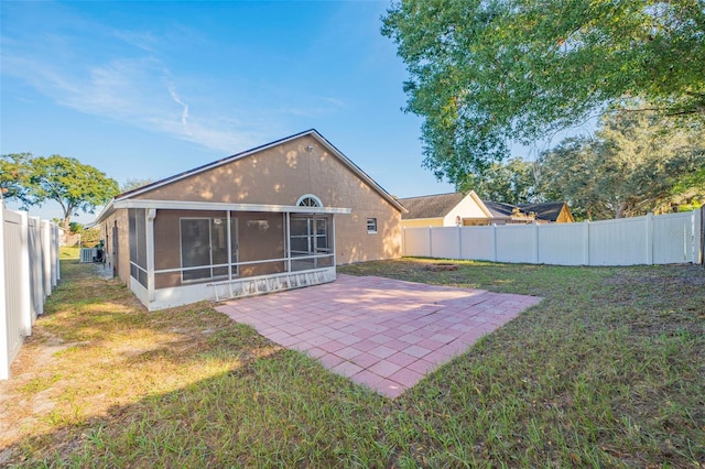 back of house featuring a lawn, a sunroom, and a patio