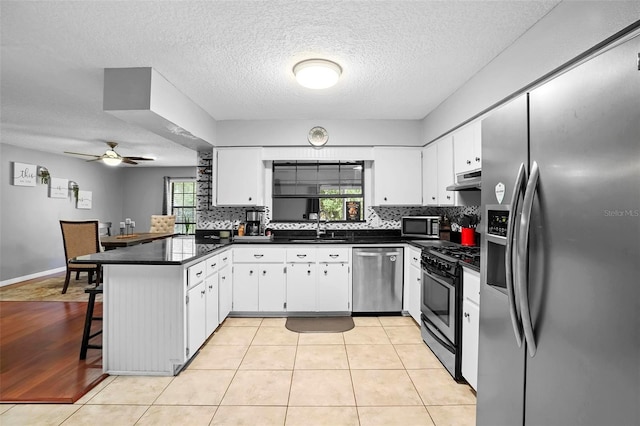 1195 Glen Royal Ter, Deland, FL 32720 - kitchen with stainless steel appliances, a peninsula, a sink, dark countertops, and backsplash